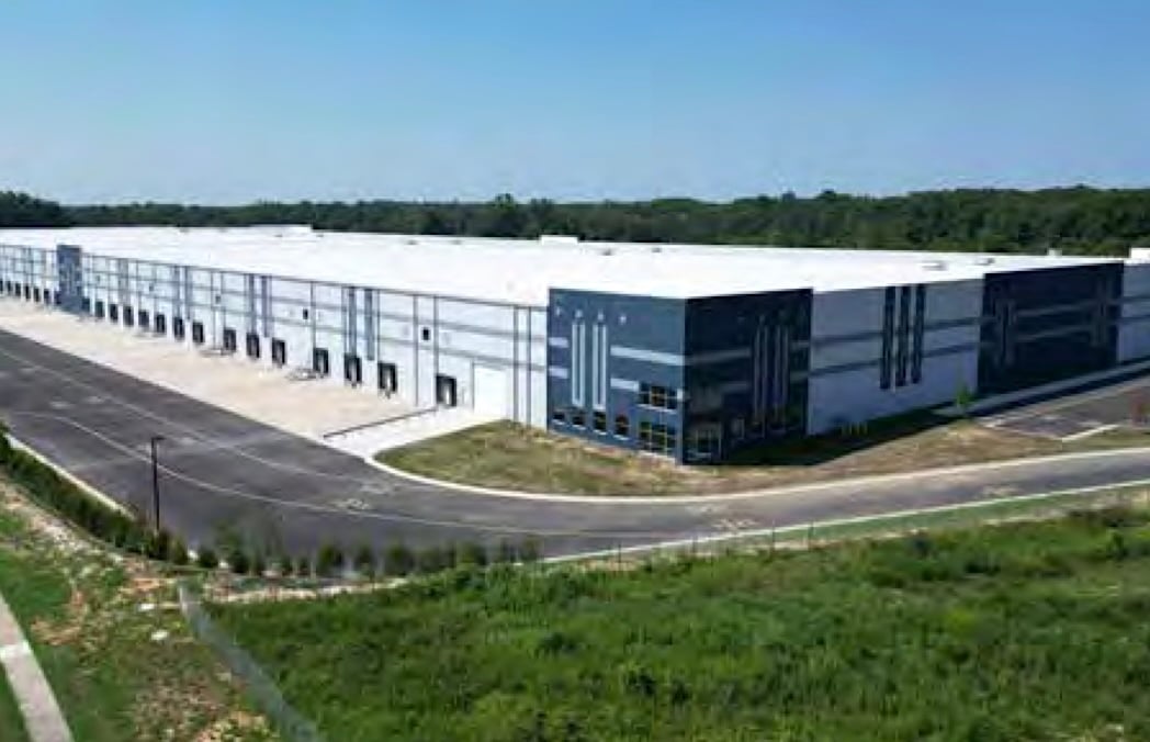 A very large warehouse building is surrounded by parking lots.