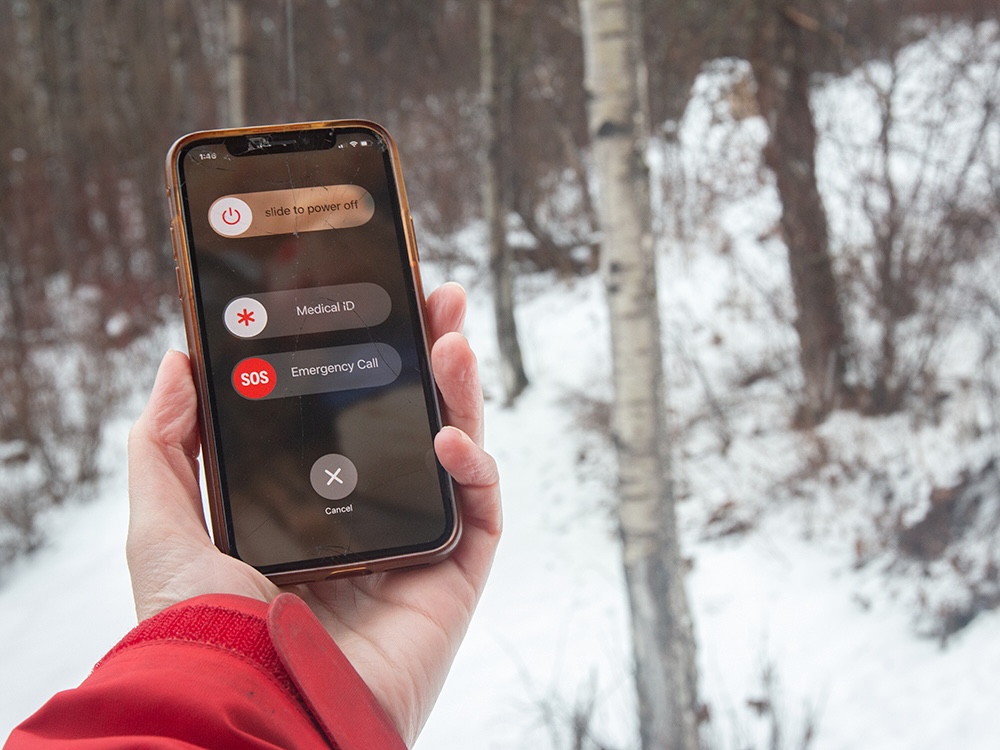 A person holds a phone in a rugged, snowy environment.