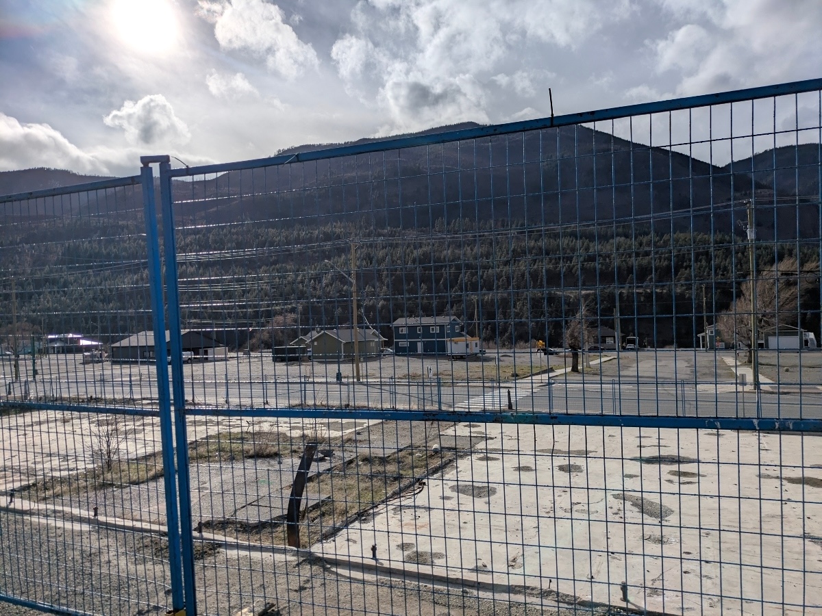 Concrete pads are visible beyond blue metal construction fencing.