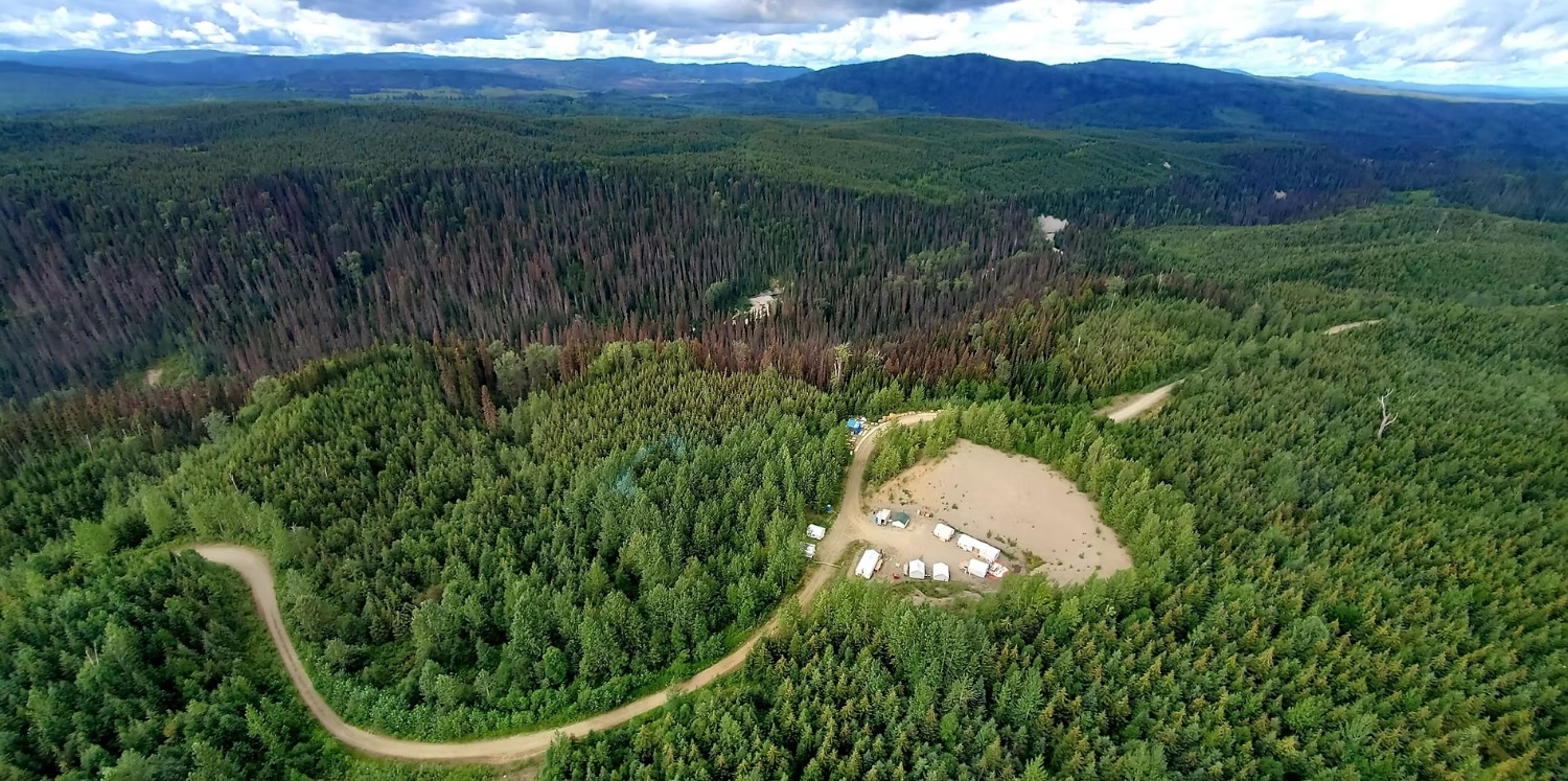 An aerial shot of a small industrial area amid a sprawling coniferous forest.