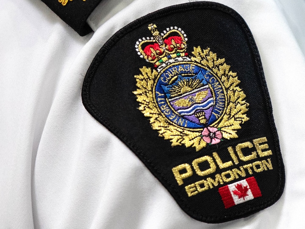 A close-up photo of an Edmonton Police officer, focusing on the cloth shoulder badge with the department's crest and motto &ndash; Integrity, Courage, Community.