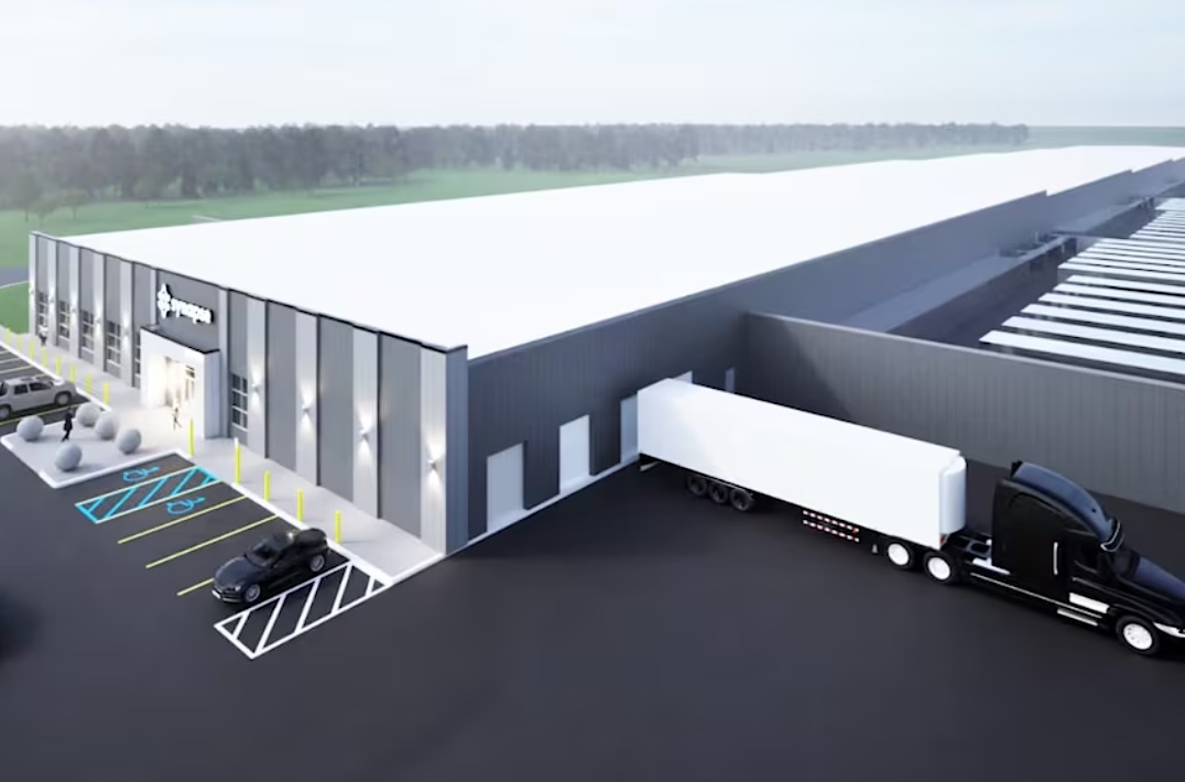 A rendered architectural image shows a grey warehouse building with a parking lot.