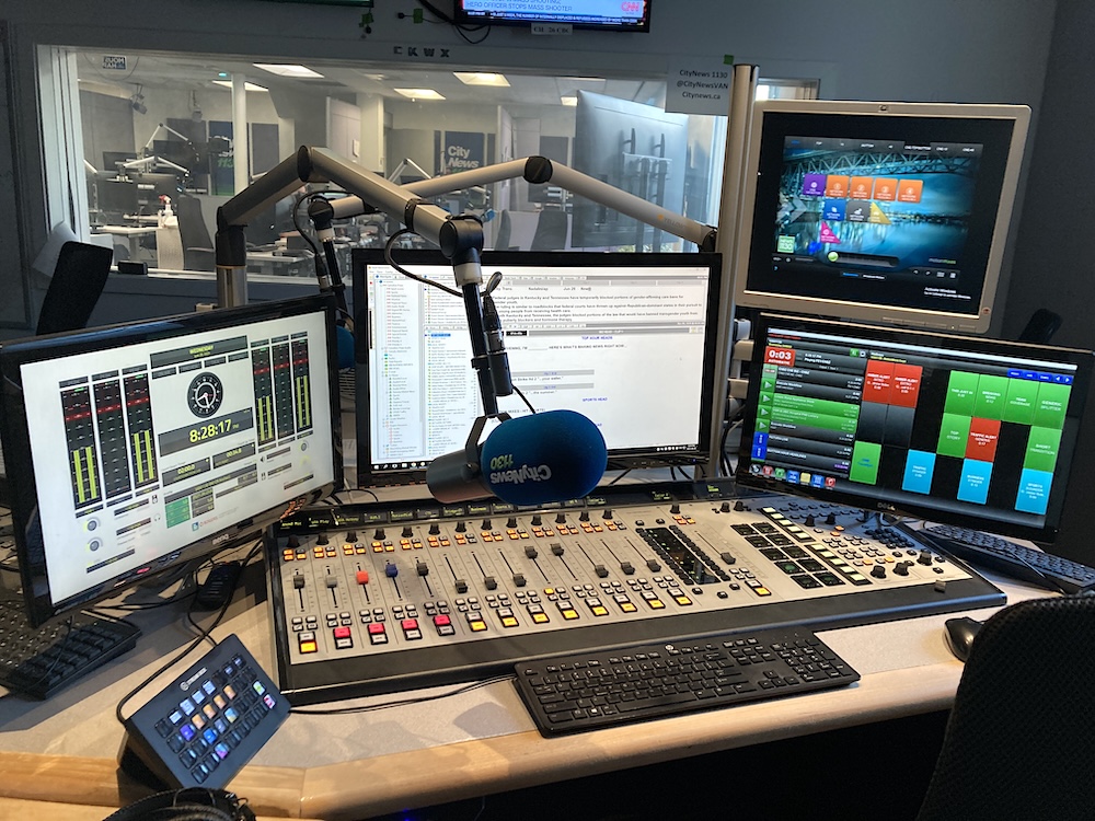 A radio broadcast booth with a microphone and mixing board.
