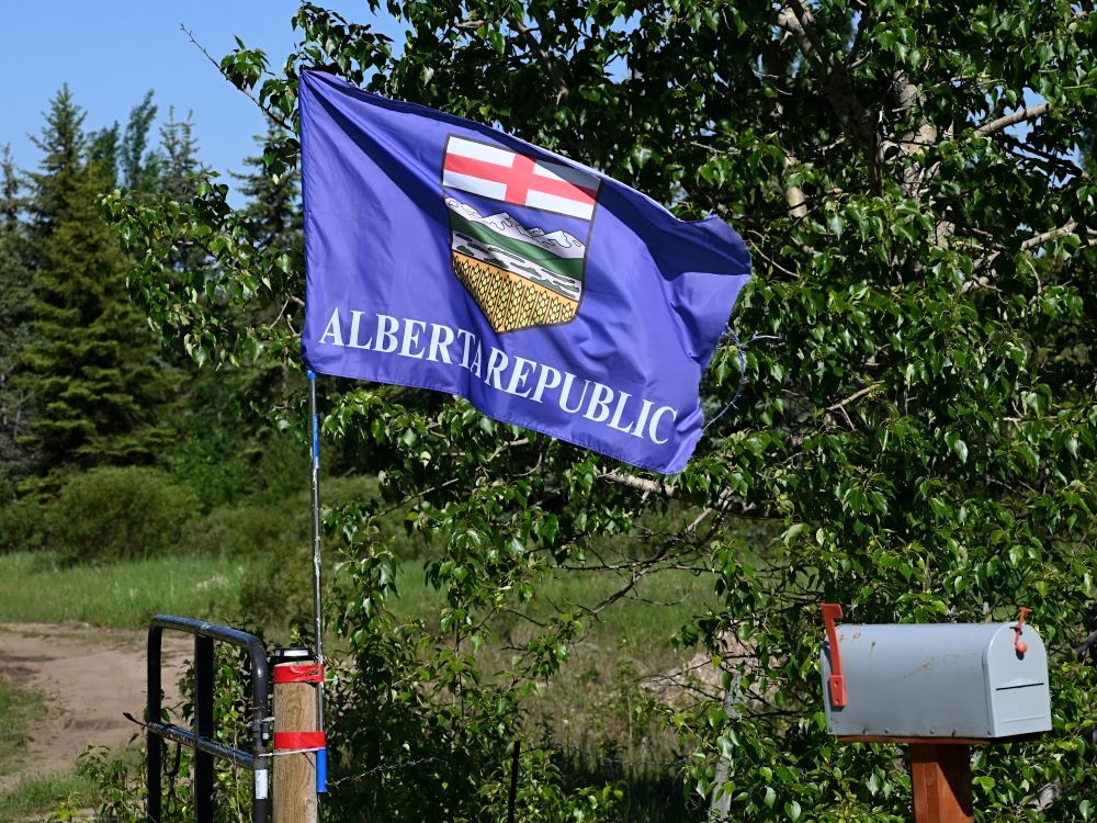 A blue flag with the Alberta crest and the words &lsquo;Alberta Republic&rsquo; flies on a short pole attached to a gate.