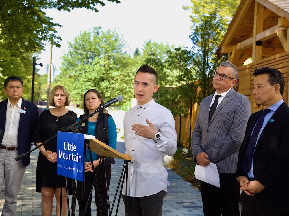 Six people stand outside a wood-frame structure.