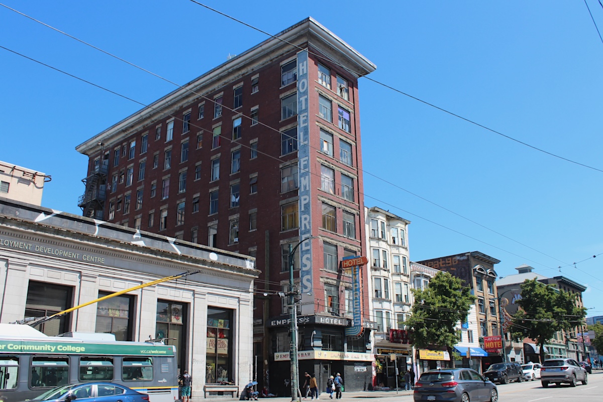 A skinny brick building on East Hastings Street with a blue and white painted sign that says &lsquo;Hotel Empress.&rsquo;