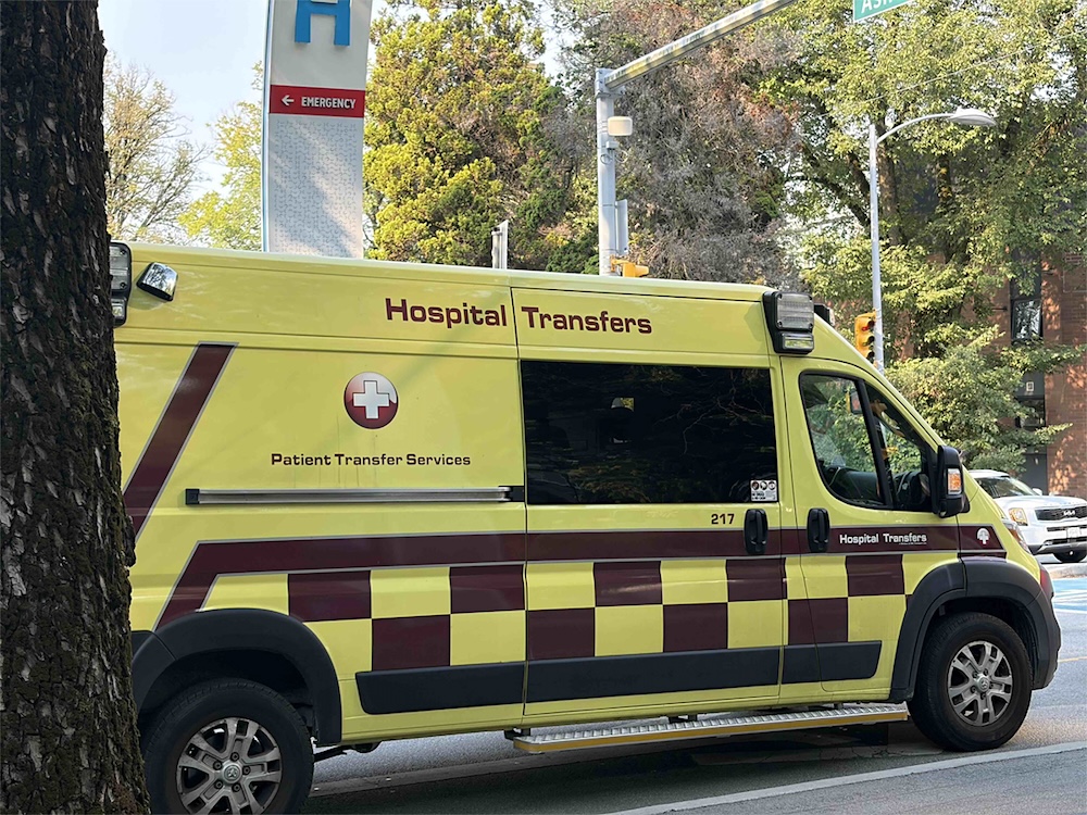 A yellow van with a checkerboard pattern and the words &lsquo;Hospital Transfers.&rsquo;