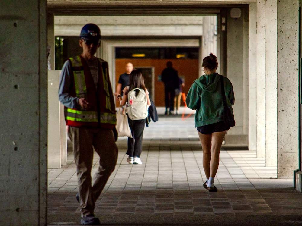 A covered concrete walkway with several people walking through the passage.