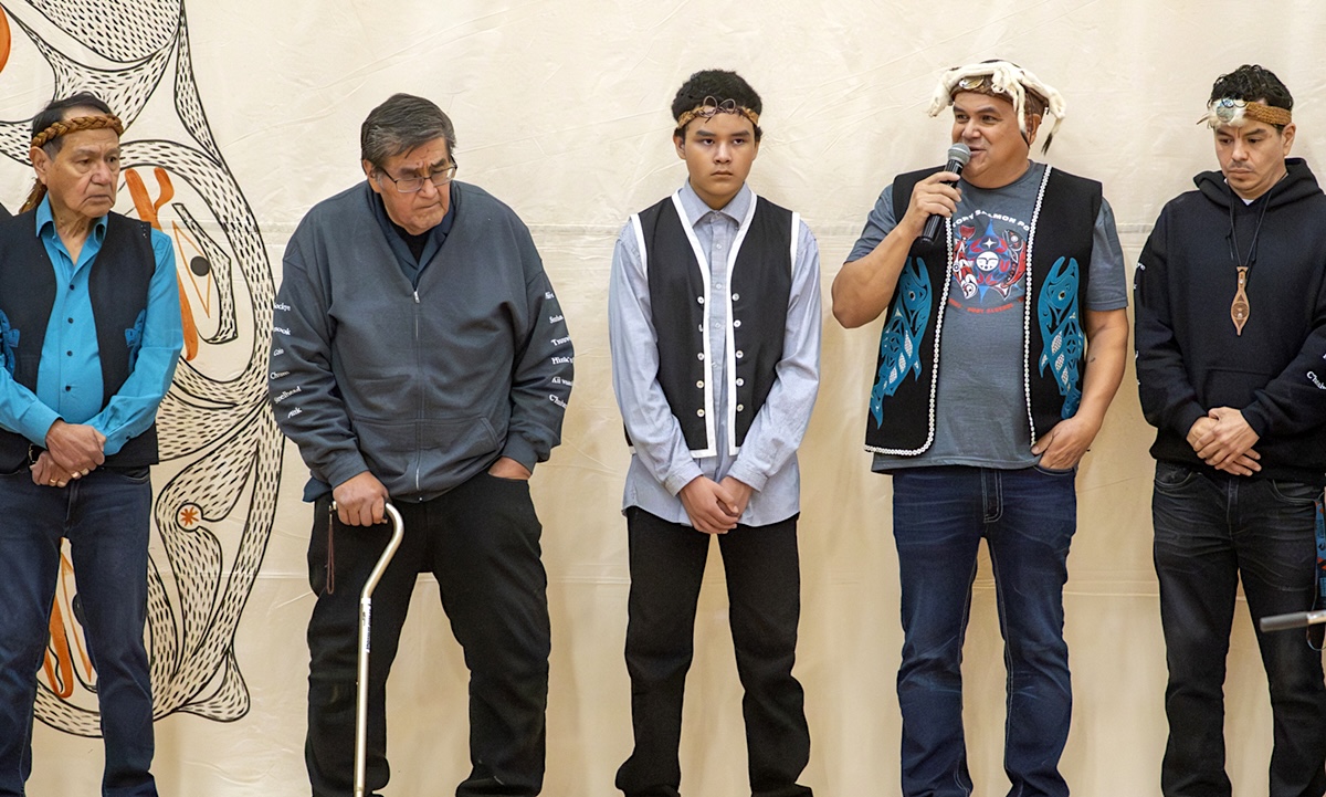 A group of five people stand and address a crowd.