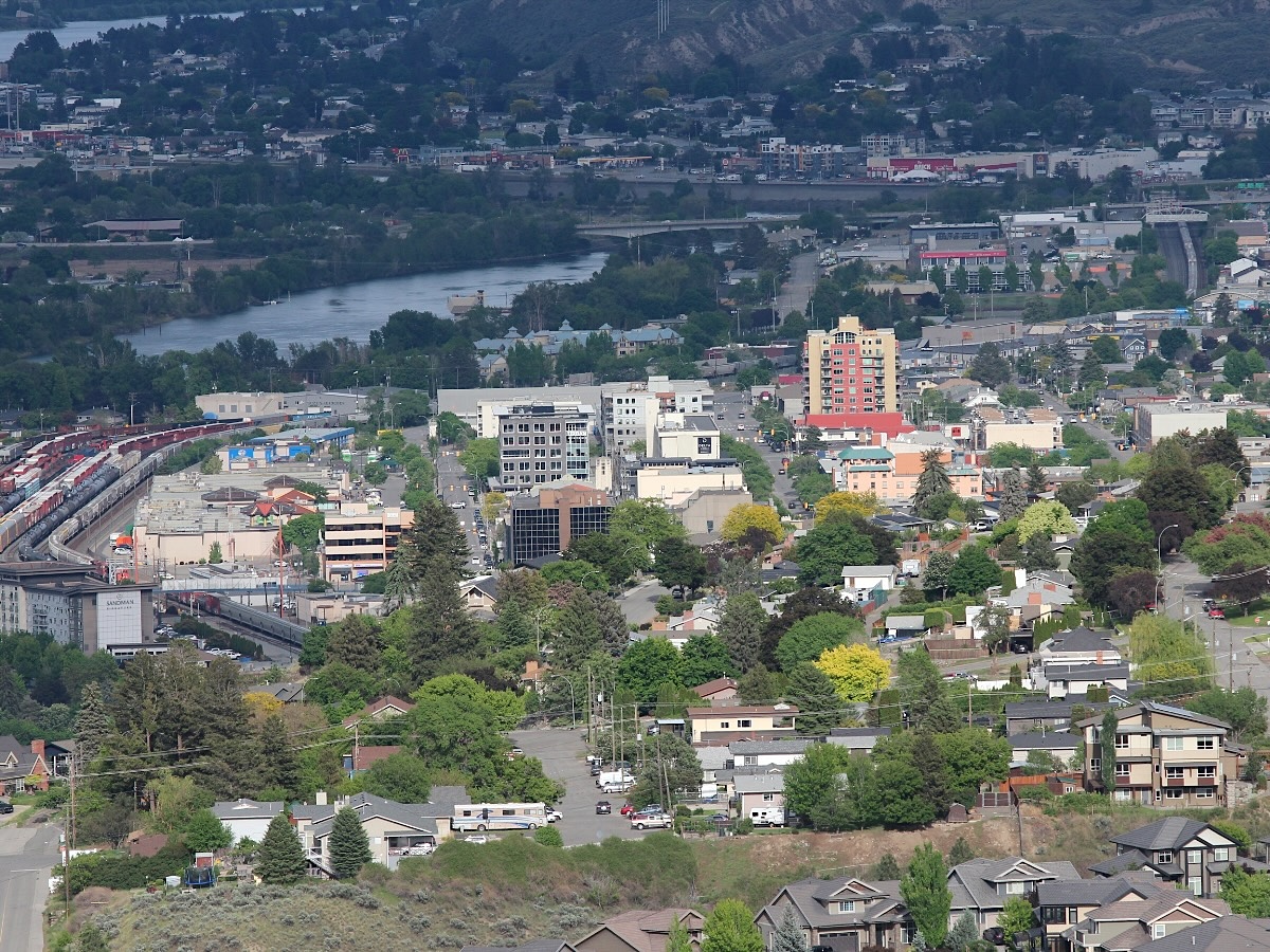 From a distance, a middle-sized city&rsquo;s core is seen illuminated in front of a river.