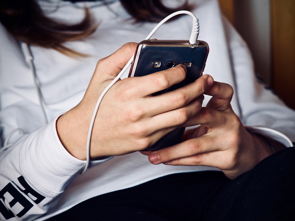 A person looks at their cellphone. Their face is not visible.