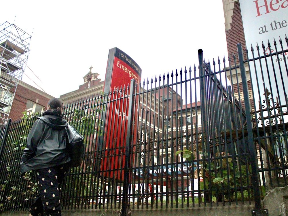 The fence outside St. Paul&rsquo;s Hospital. A person walks by.