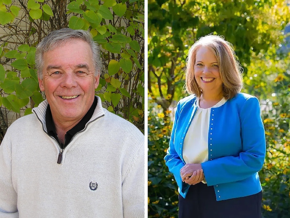 Ron Paul has grey hair and is wearing a grey sweater with a zipper. Coralee Oakes has blond hair and is wearing a blue blazer.