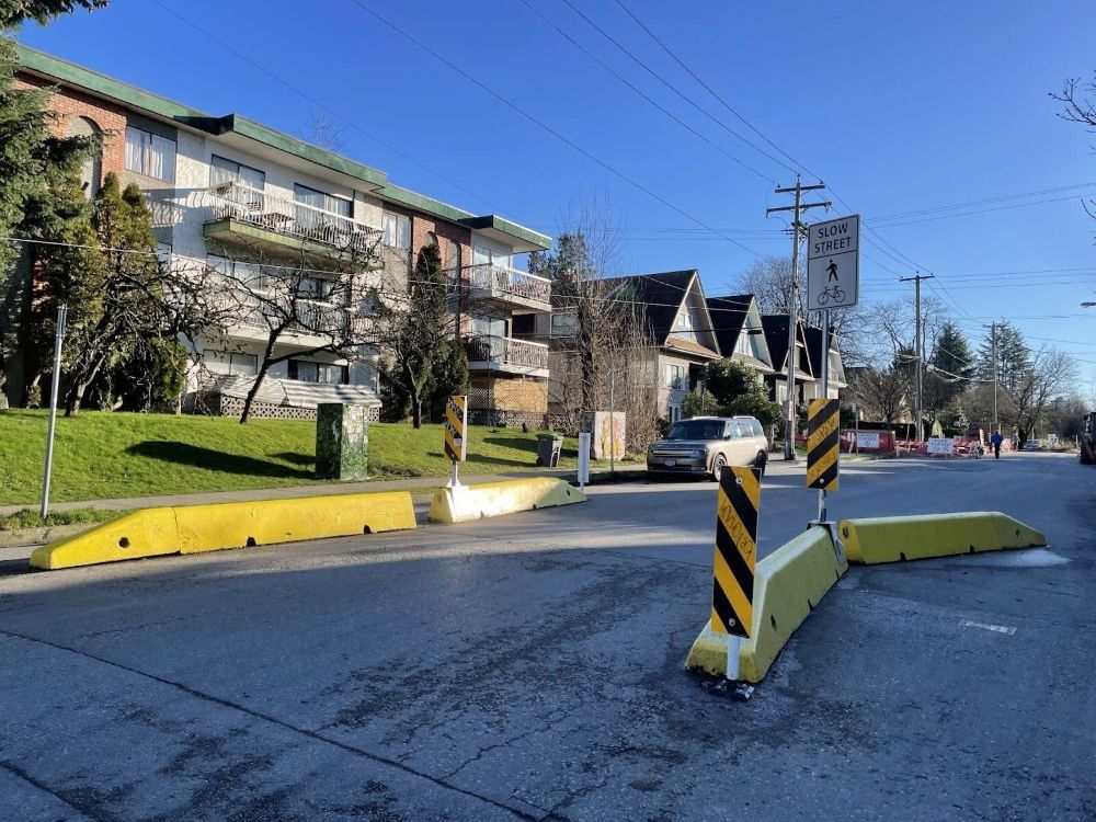 A street in East Vancouver with bright yellow concrete barriers making the street narrower.