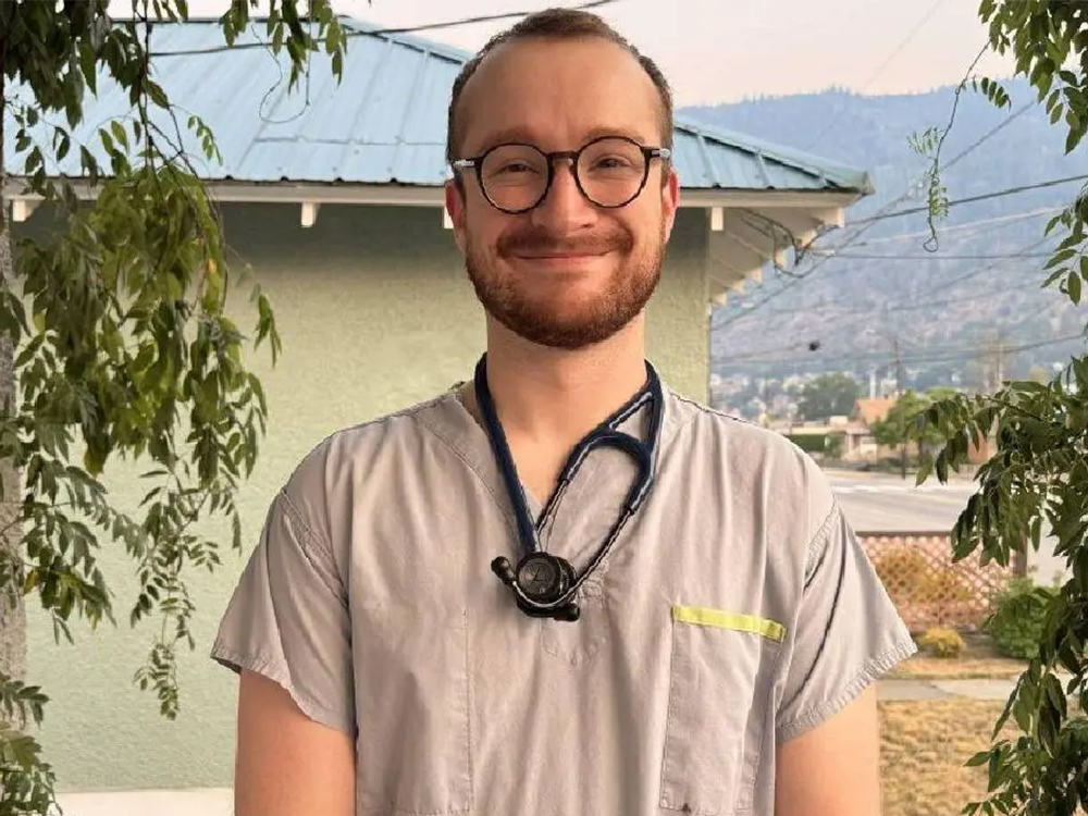A doctor wears a stethoscope and stands in Grand Forks in the summertime. 