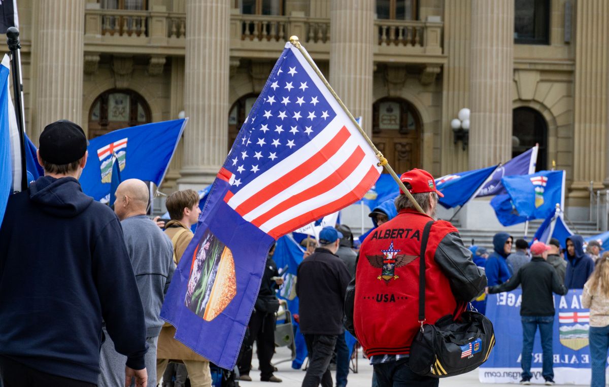 Rally goer with blue Alberta independence flags and one participant carrying the red, white and blue U.S. flag.