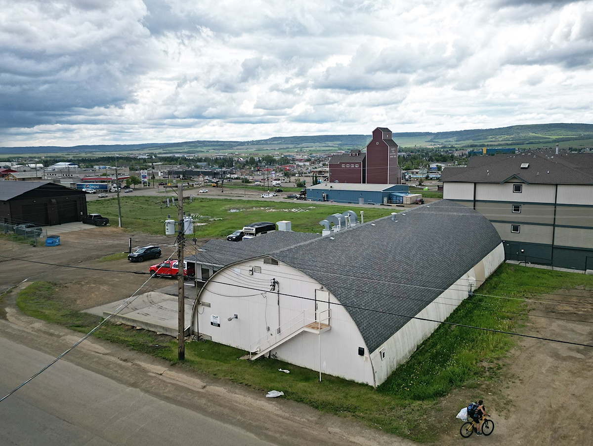 An aerial photo of a Quonset hut with the city of Dawson Creek beyond.