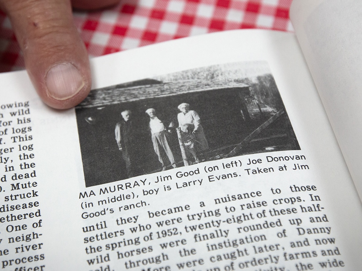A black and white photo in a book with the caption &lsquo;Ma Murray, Jim Good (on left), Joe Donovan (in middle), boy is Larry Evans.&rsquo; 