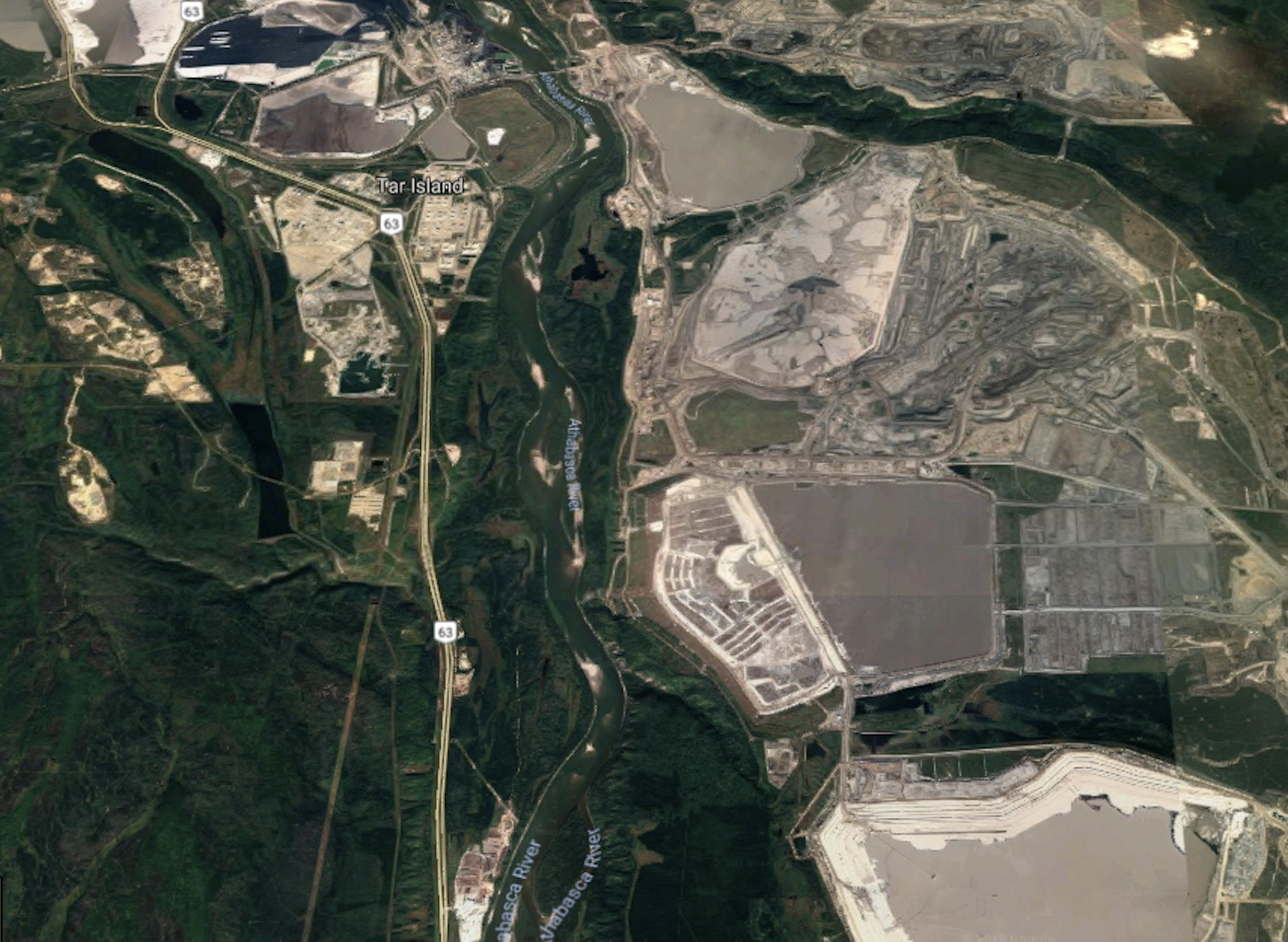 An aerial photo shows a vast oilsands facility carved out of the forest, including huge tailing ponds for mining waste.