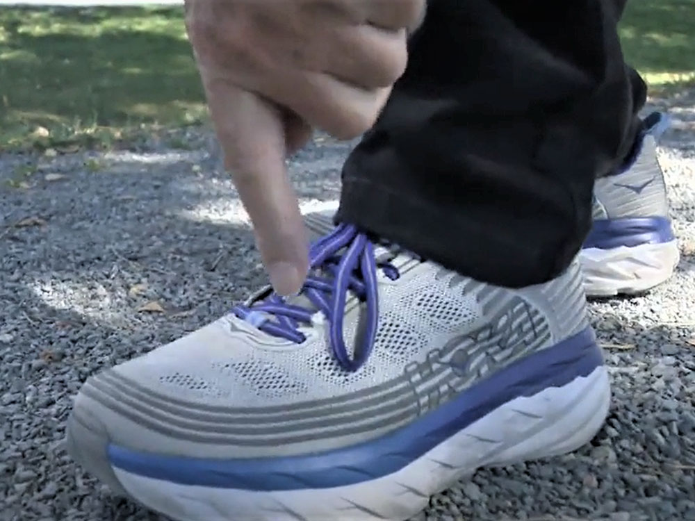 A close-up of a running shoe on a foot with an index finger, belonging to Surrey Mayor Doug McCallum, pointing down at the toe area.