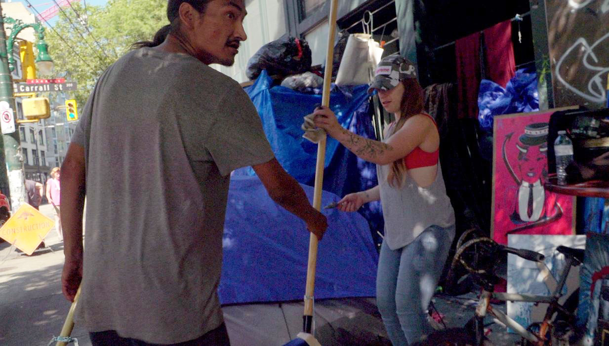 Aaron hands a broom to an unidentified woman on his right, on Carrall Street in Vancouver’s Downtown Eastside. 