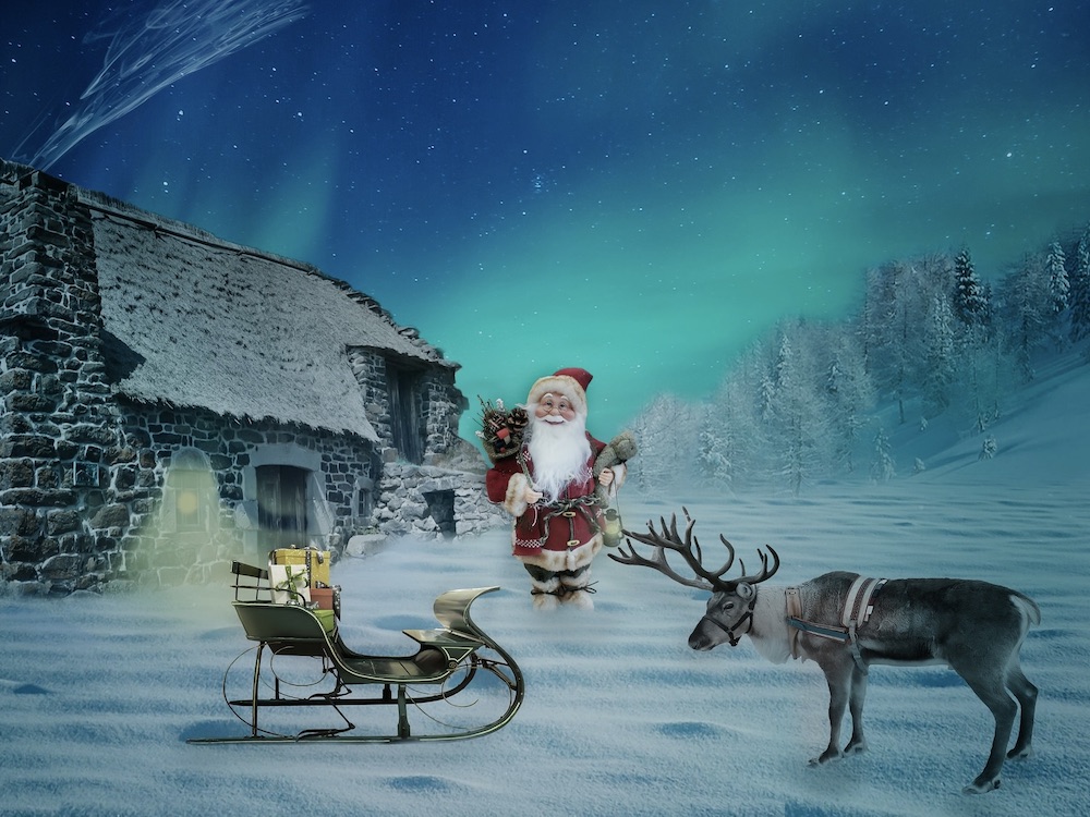 An illustration of Santa standing in front of a snowy house, with a sleigh and a reindeer.