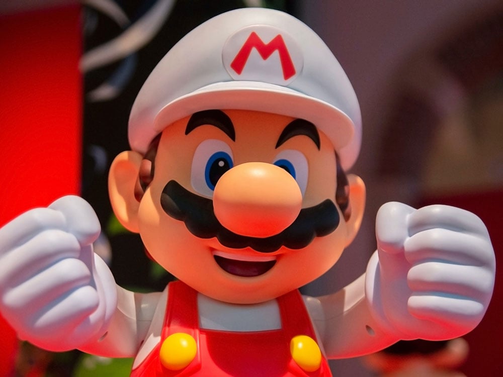 A luridly coloured image shows Super Mario, a video game character, wearing a white helmet, red coveralls and white gloves and reaching toward the viewer.
