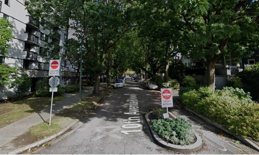 A Google Street View image of the 10th Avenue bike route displays two red “do not enter” signs that exclude all traffic but bicycles along a shady, tree-lined residential street on a sunny day.