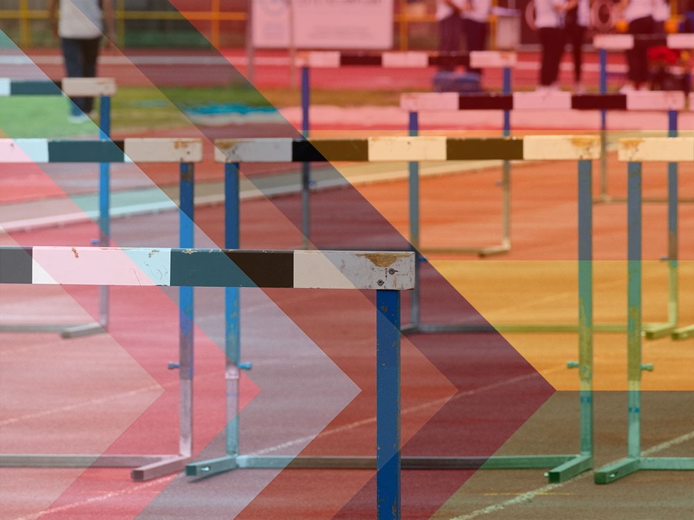 A photo of black and white barriers on a running track is overlaid with rainbow colourways.