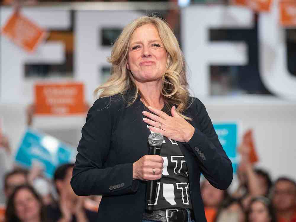 Rachel Notley stands on a platform, holding a microphone, during a 2023 election campaign rally.