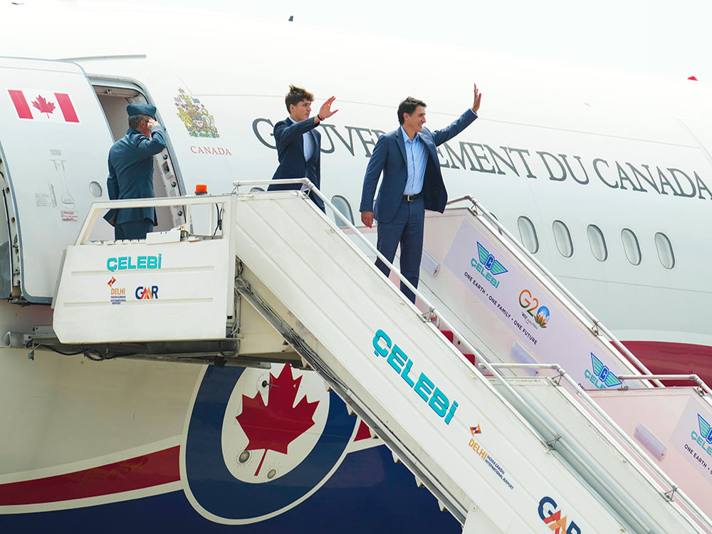 Prime Minister Justin Trudeau and son Xavier wave from the steps leading into a Government of Canada airplane.