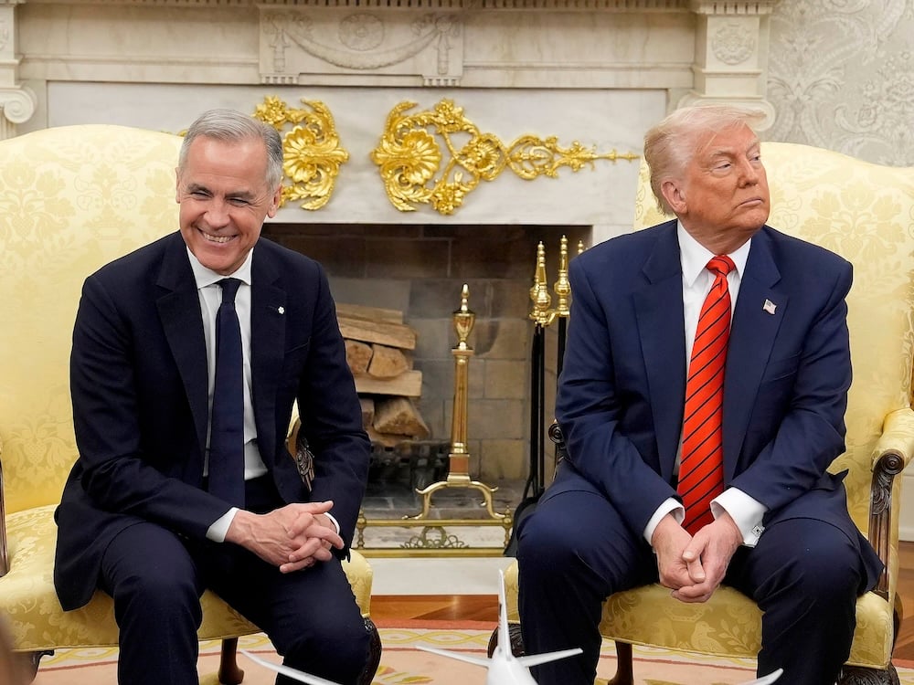 Prime Minister Mark Carney smiles as U.S. President Donald Trump looks away. Both are seated in an ornately decorated office.