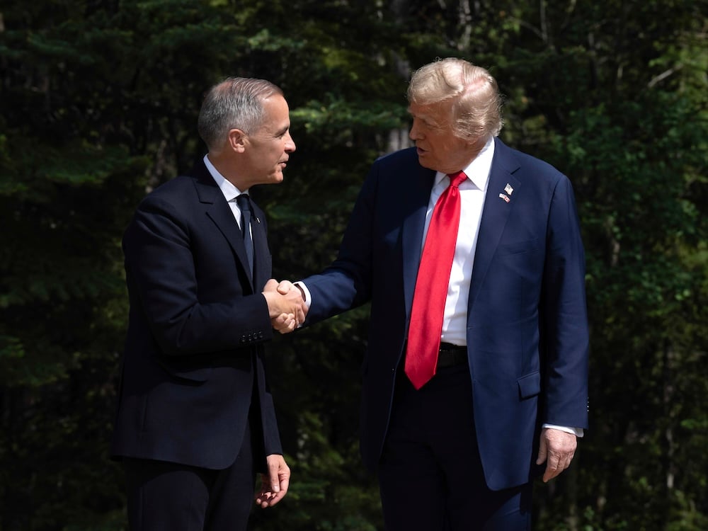 Mark Carney, a 60-year-old light-skinned man in a suit, shakes hands with Donald Trump, also in a suit with a long red tie.