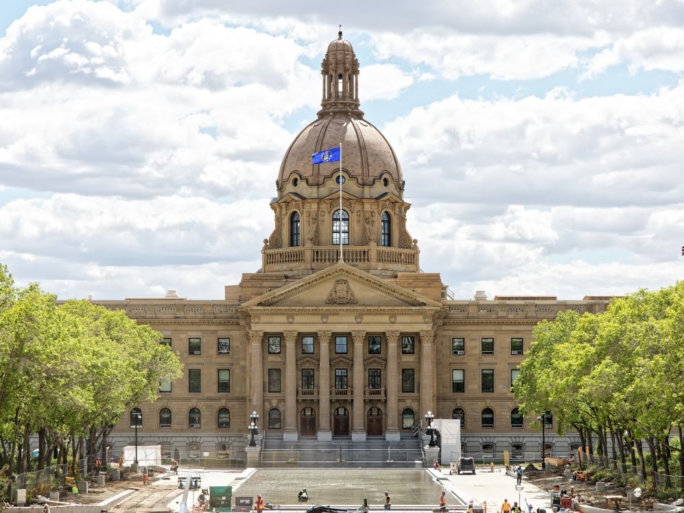 The Alberta legislature is an ornate grey building flying the province&rsquo;s flag on a sunny day.