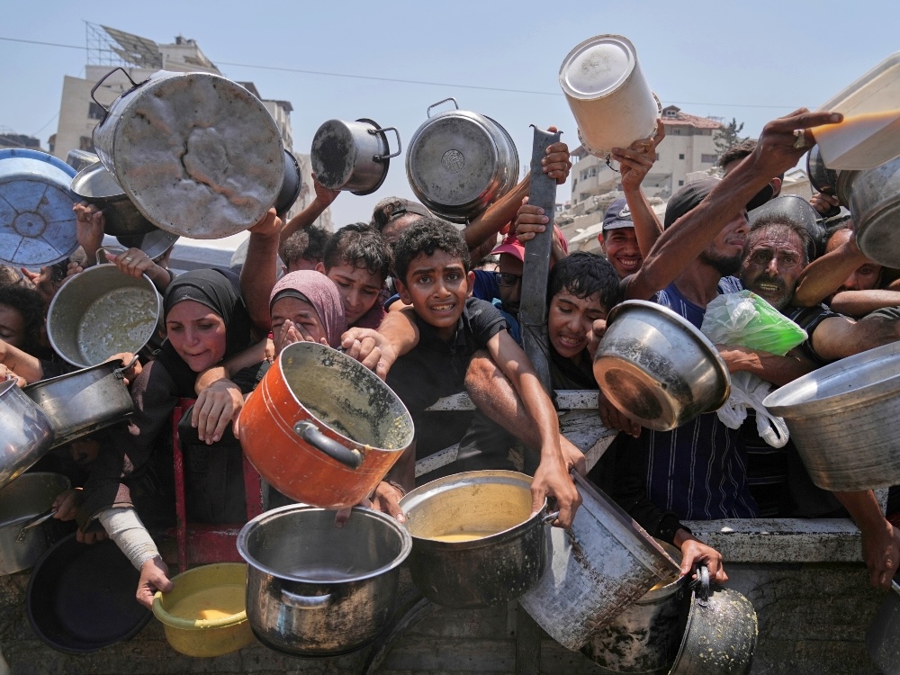 People in the Gaza Strip thrusting pots forward to attempt to access food assistance.
