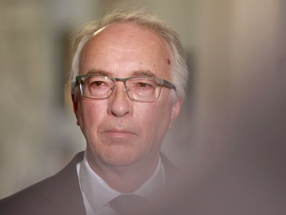 A middle-aged white man wearing a suit and tie has a pensive expression.