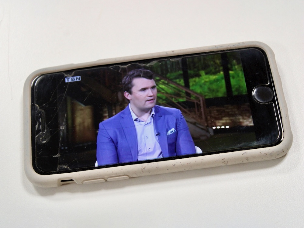 A video of a light-skinned man with short brown hair and wearing a blue blazer plays on an iPhone.