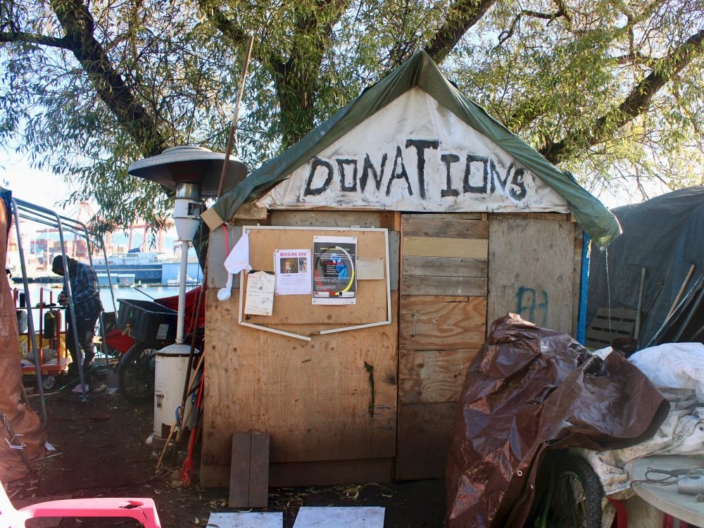 A rough wooden shack with a sign reading &lsquo;Donations&rsquo; at a waterfront park in Vancouver.