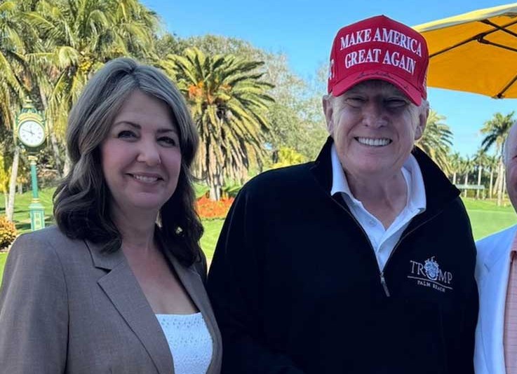 Danielle Smith poses with Donald Trump, who is wearing a red MAGA hat.