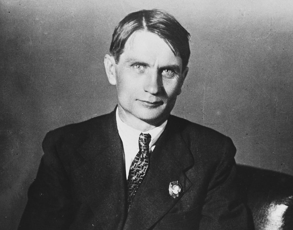 A black and white photo of a man with light skin tone and short straight hair wearing a suit.