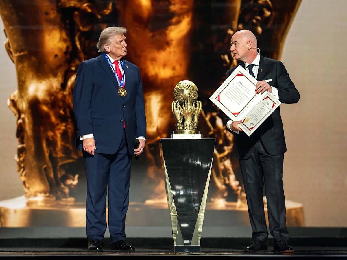 Donald Trump and Gianni Infantino stand on a stage with a big ugly gold cup. 
