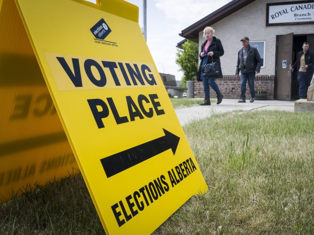 A yellow voting place sign outside a community hall in a small town in Alberta.