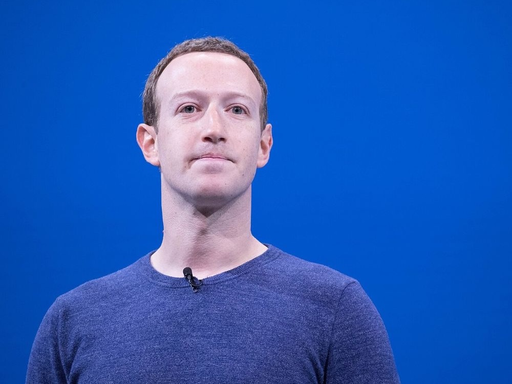 A man stands in front of a blue background.
