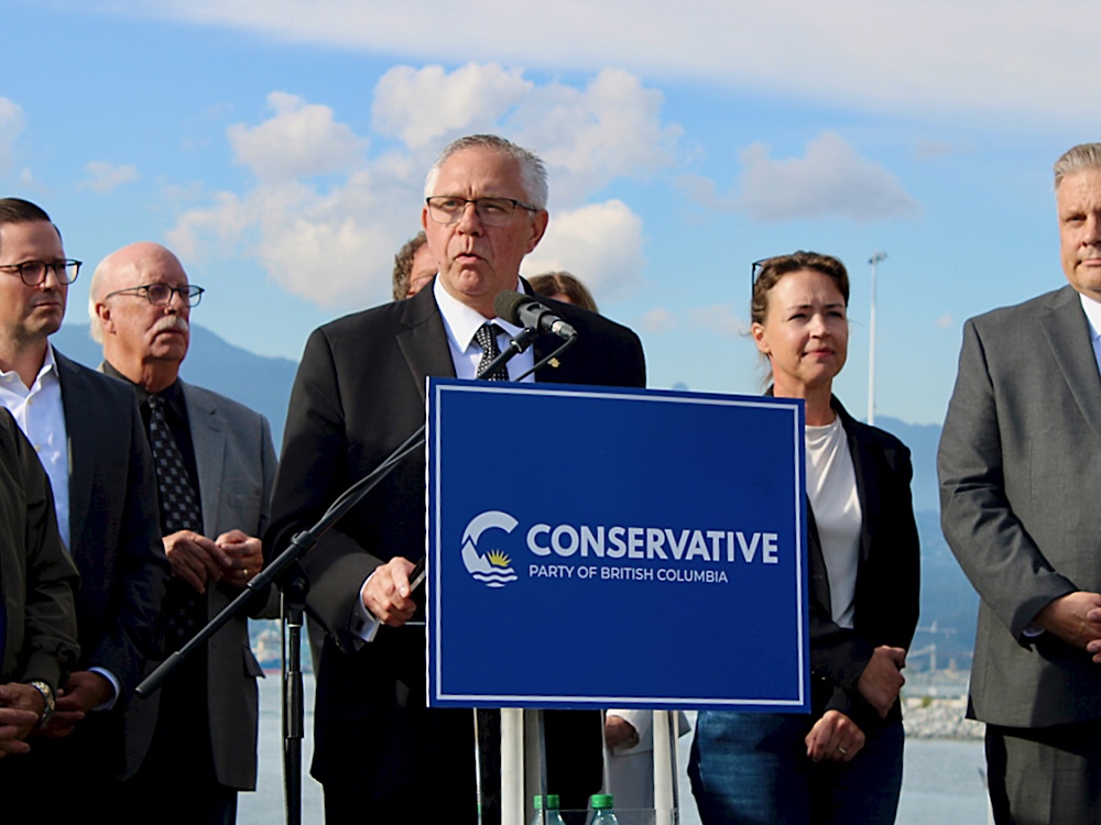 Lorne Doerkson stands at a lectern that reads &lsquo;Conservative Party of British Columbia&rsquo; in front of the port in Vancouver.