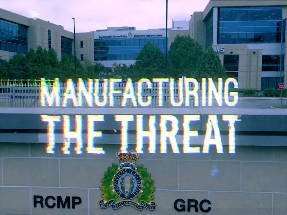The exterior of an RCMP building. There is text overlay reading ‘Manufacturing the Threat’ in the style of an old television with a bad signal.