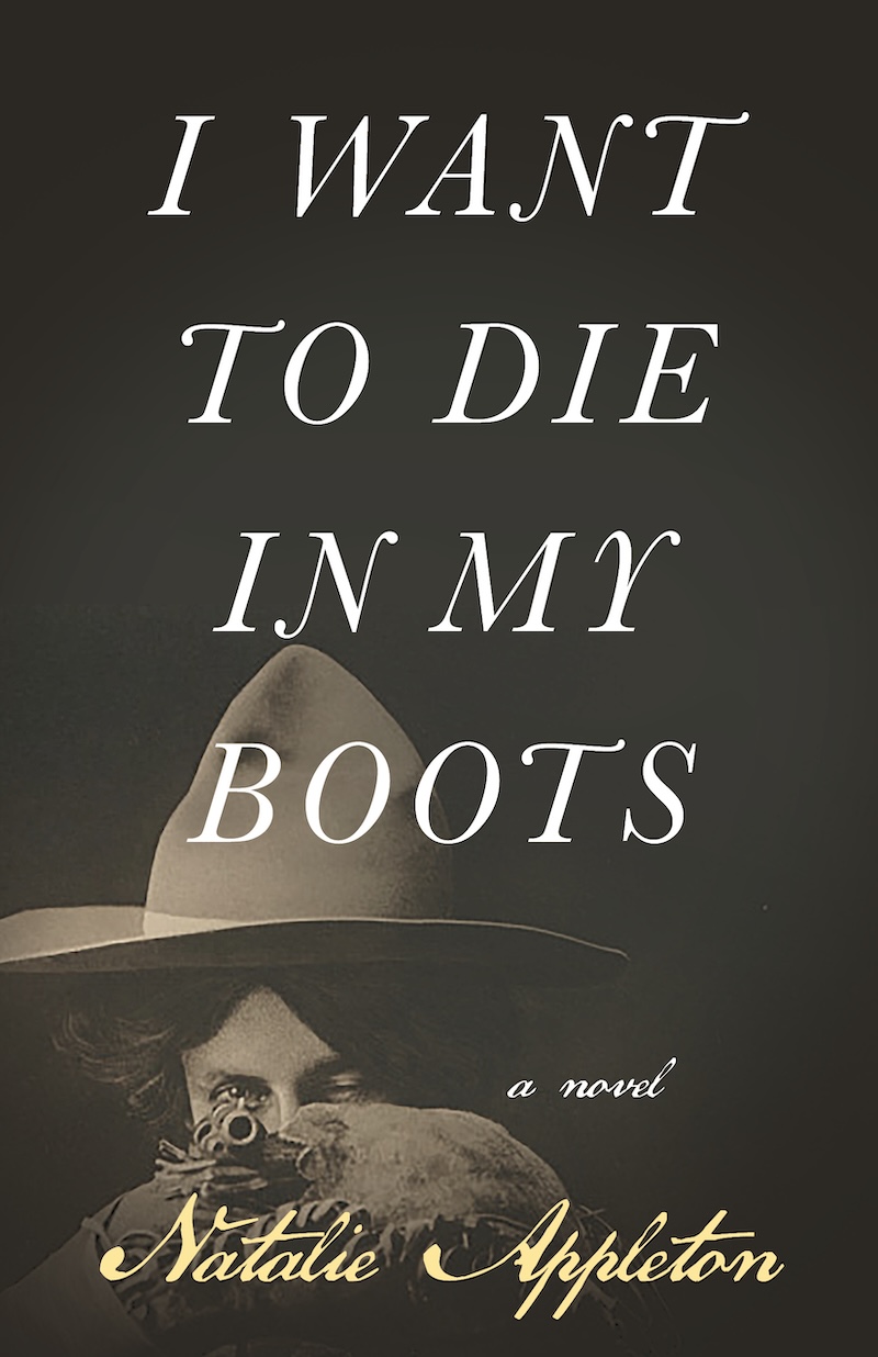 The book cover of ‘I Want to Die in My Boots’ by Natalie Appleton features a sepia-toned image of a woman in a cowboy hat with only her eyes visible over the barrel of a gun she is pointing.