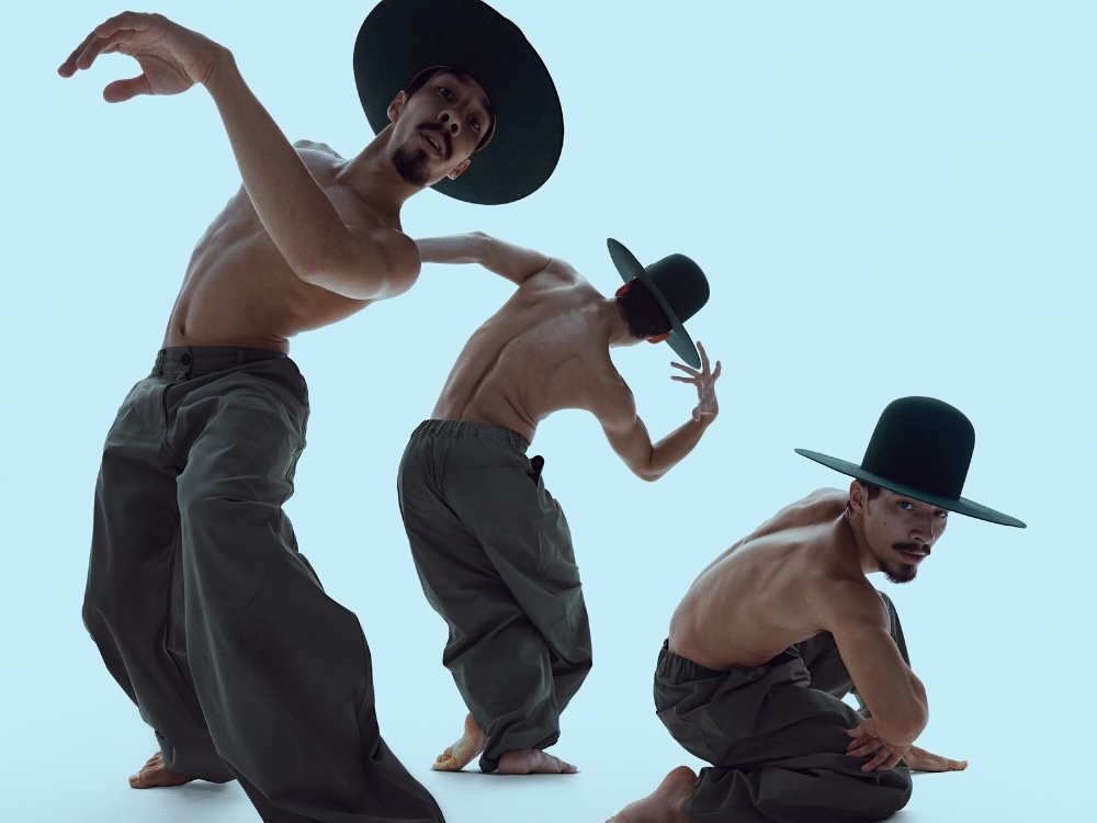 A dancer wears a wide-brimmed hat and baggy green cargo pants. There are three photos of him, which have been edited to capture a wave-like dance sequence. He appears against a light blue background.