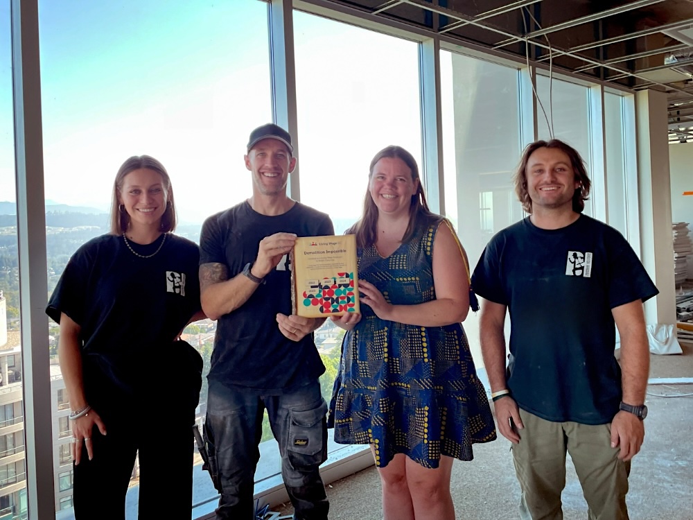 Four staff members from Demolition Impossible accept their Living Wage BC certification plaque.