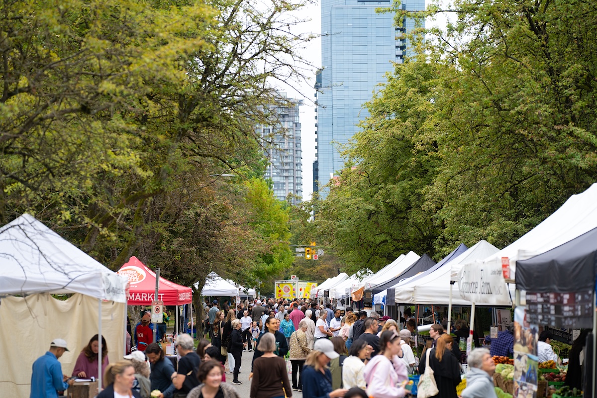 Crowds of people fill an urban farmers market.