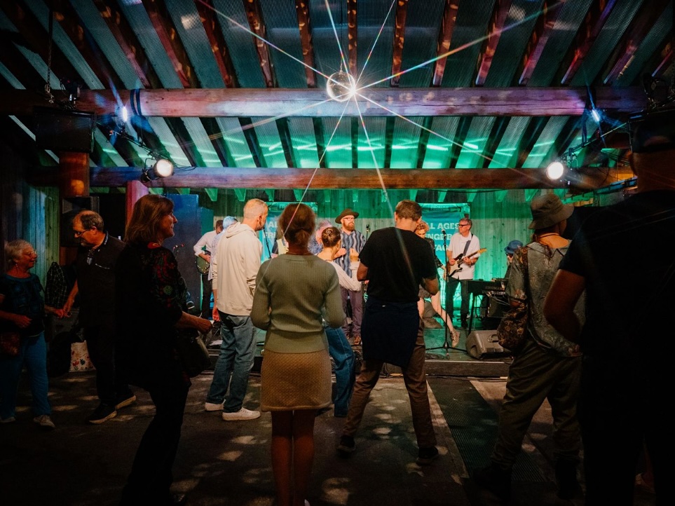 People on a dance floor under a disco ball with a band playing in front of them.